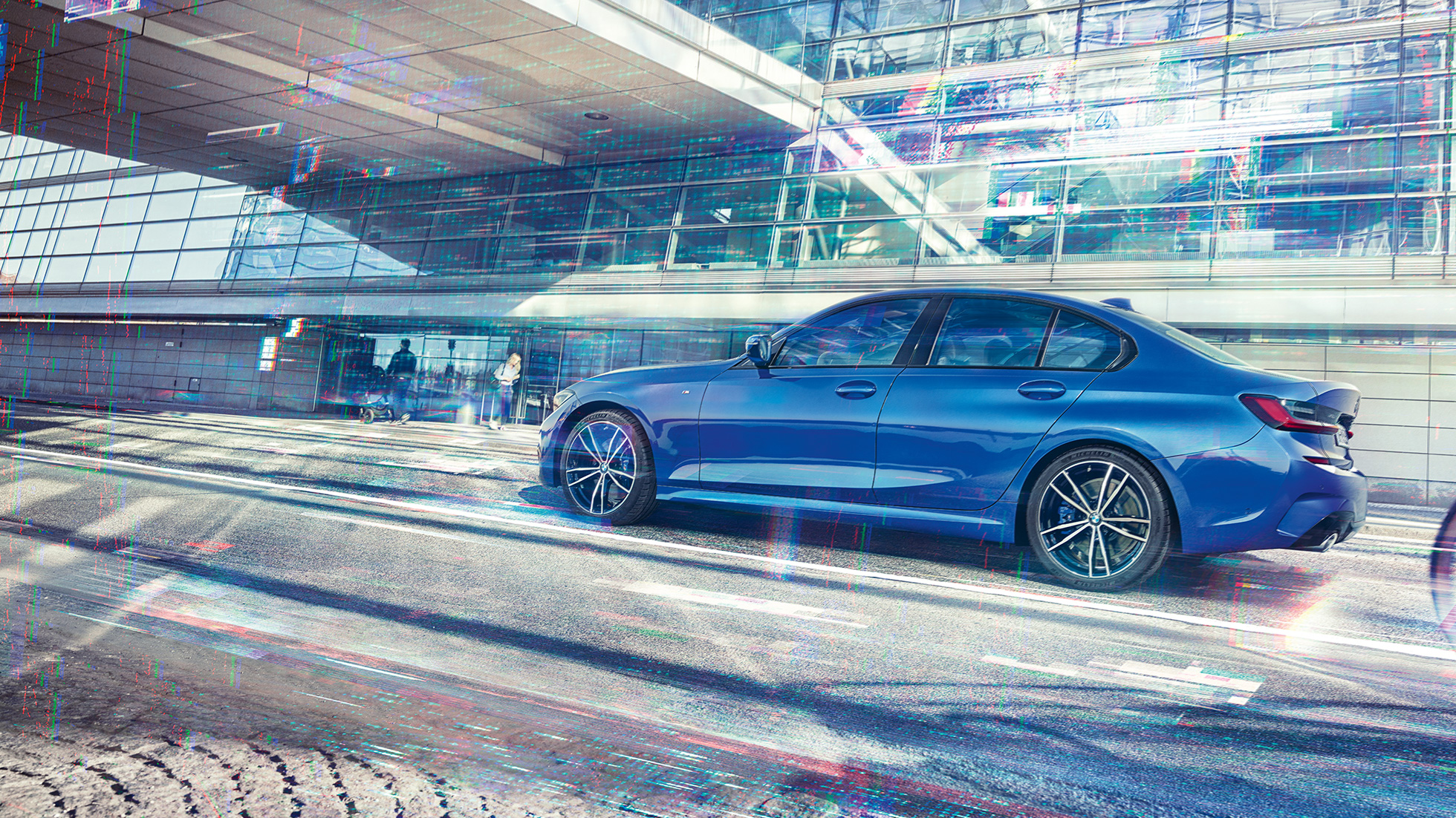 BMW 3 Series Sedan, side view. G20 Still shot of the BMW 3 Series Sedan from the side on the day in front of a glass building. G20