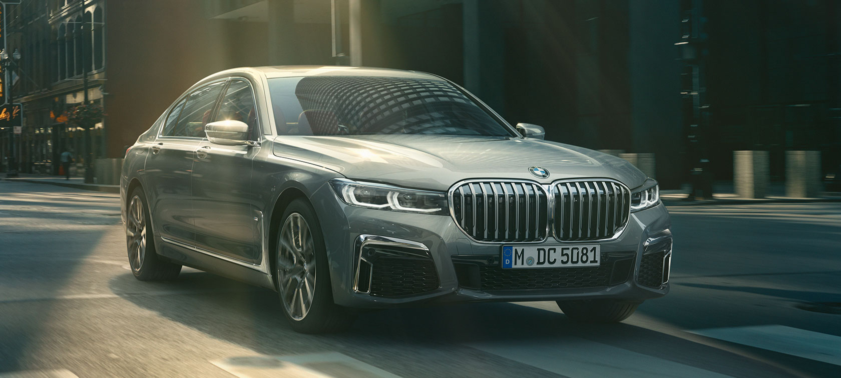 Grey BMW 7 Series Sedan driving, three-quarter front view G11 Grey BMW 7 Series Sedan drives through the urban setting in the three-quarter front view G11