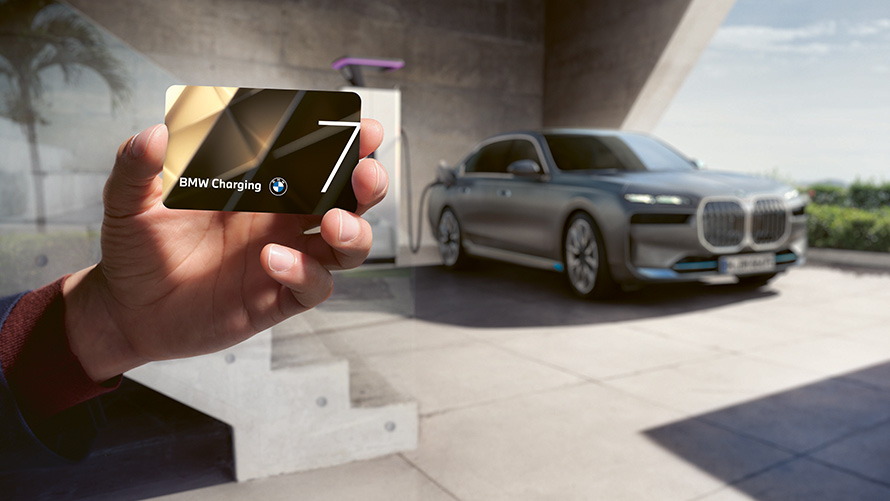 BMW Charging Charging Package BMW i7 Sedan G70 BMW i7 Sedan G70 BMW Charging Charging Package BMW Charging Card holding in hand with BMW i7 in background