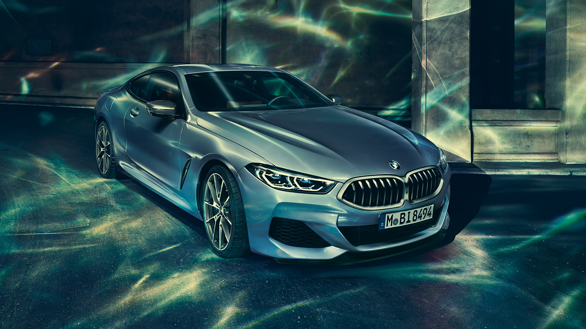 BMW M850i xDrive Coupé, three-quarter front view left. BMW M850i xDrive Coupé in Barcelona Blue metallic, three-quarter front view left, standing in front of building.