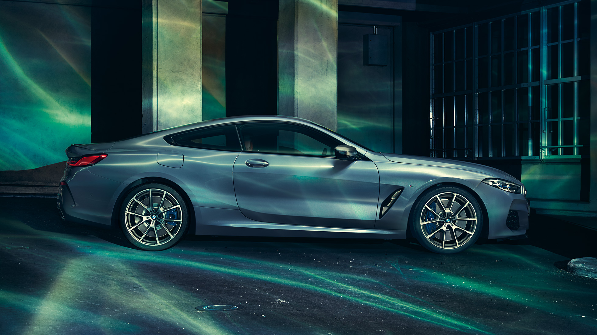 BMW M850i xDrive Coupé, side view. BMW M850i xDrive Coupé in Barcelona Blue metallic, side view, standing in front of building.