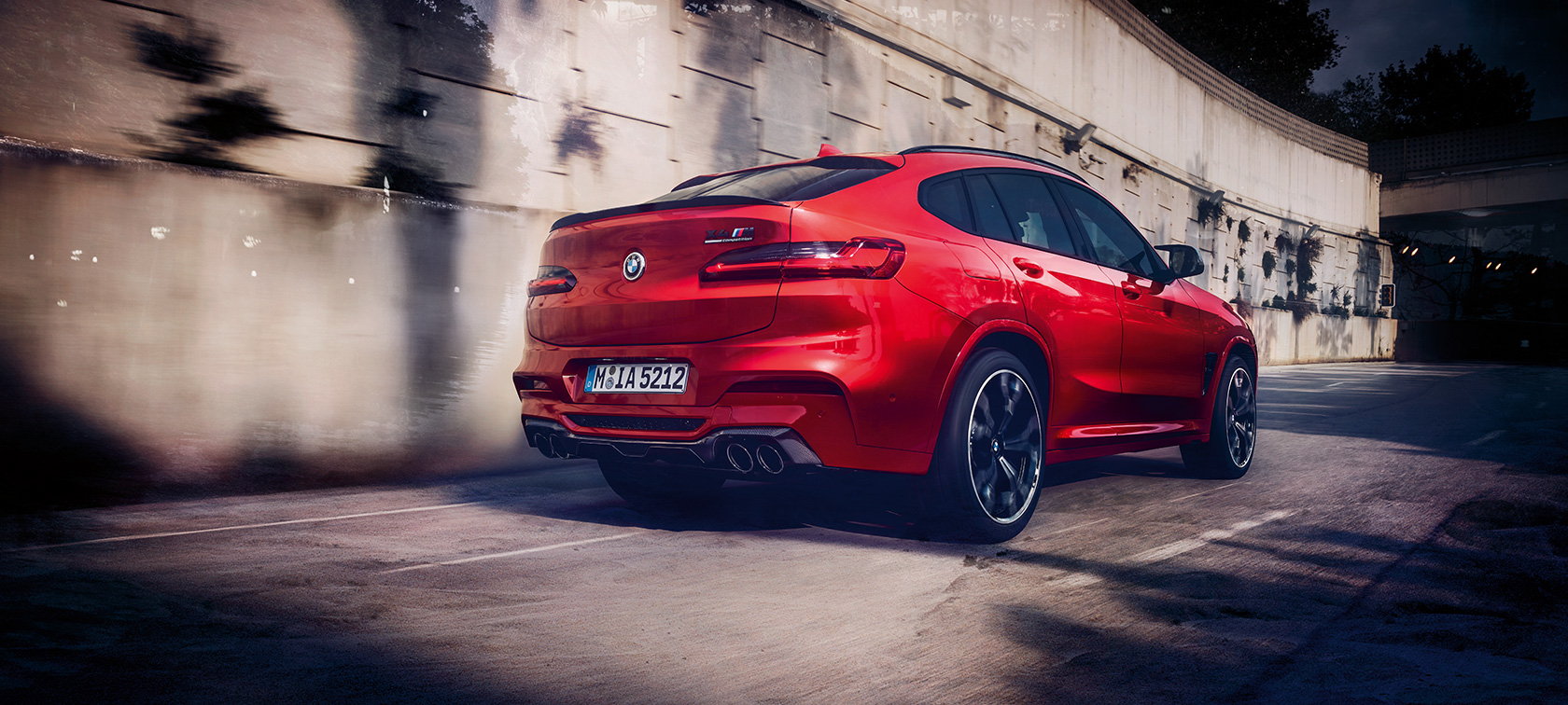 BMW X4 M Competition, three-quarter rear view. F98 BMW X4 M Competition in Toronto Red metallic, driving, exterior, three-quarter rear view. F98