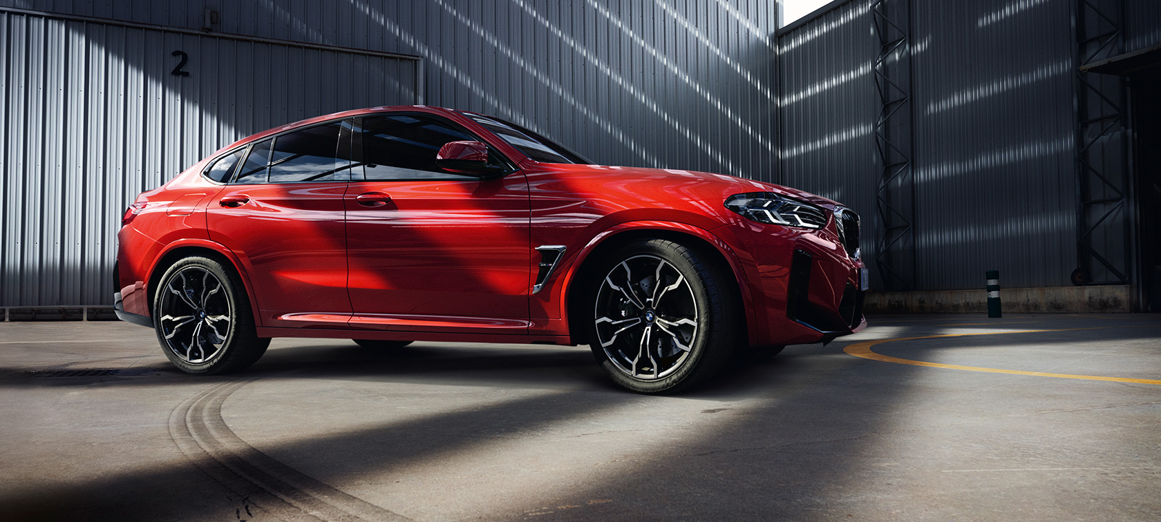 Three-quarter front view BMW X4 M F98 LCI Facelift 2021 BMW X4 M F98 LCI Facelift 2021 Toronto Red Metallic three-quarter front view inside factory building