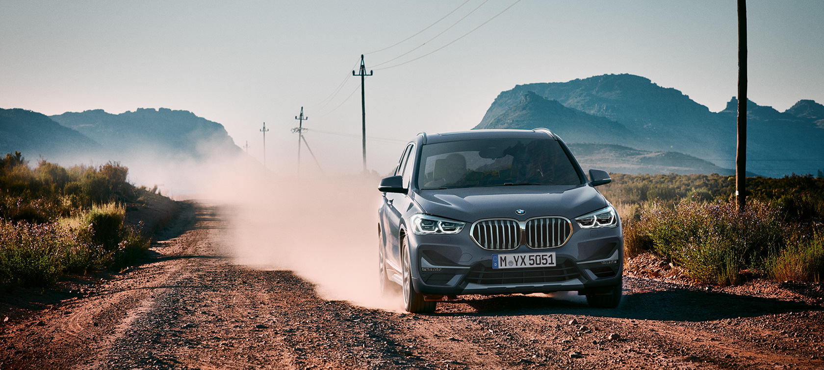 BMW X1, three-quarter rear view. F48 BMW X1, three-quarter rear view driving in front of mountain scenery. F48