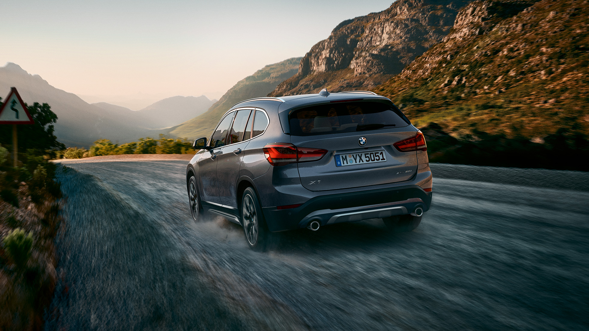 BMW X1, three-quarter rear view. F48 BMW X1, three-quarter rear view driving in front of mountain scenery. F48