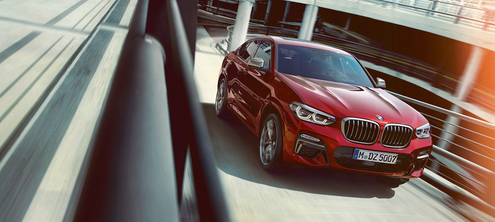 BMW X4 driving in the multi-storey car park G02 BMW X4 G02 2018 Flamenco Red brilliant effect three-quarter side view driving in the multi-storey car park