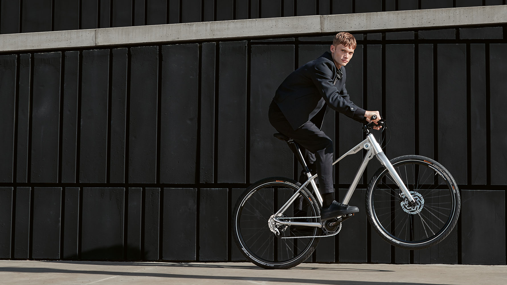The picture shows a young man doing a dynamic ‘wheelie’ on a BMW Cruise Bike. The picture shows a young man doing a dynamic ‘wheelie’ on a BMW Cruise Bike.