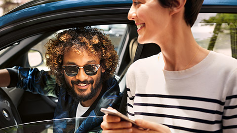 Man sitting in BMW and woman with smartphone BMW Financial Services man sitting in BMW and woman with smartphone